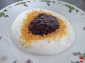 Biely jogurt s malinovým džemom a cornflakes